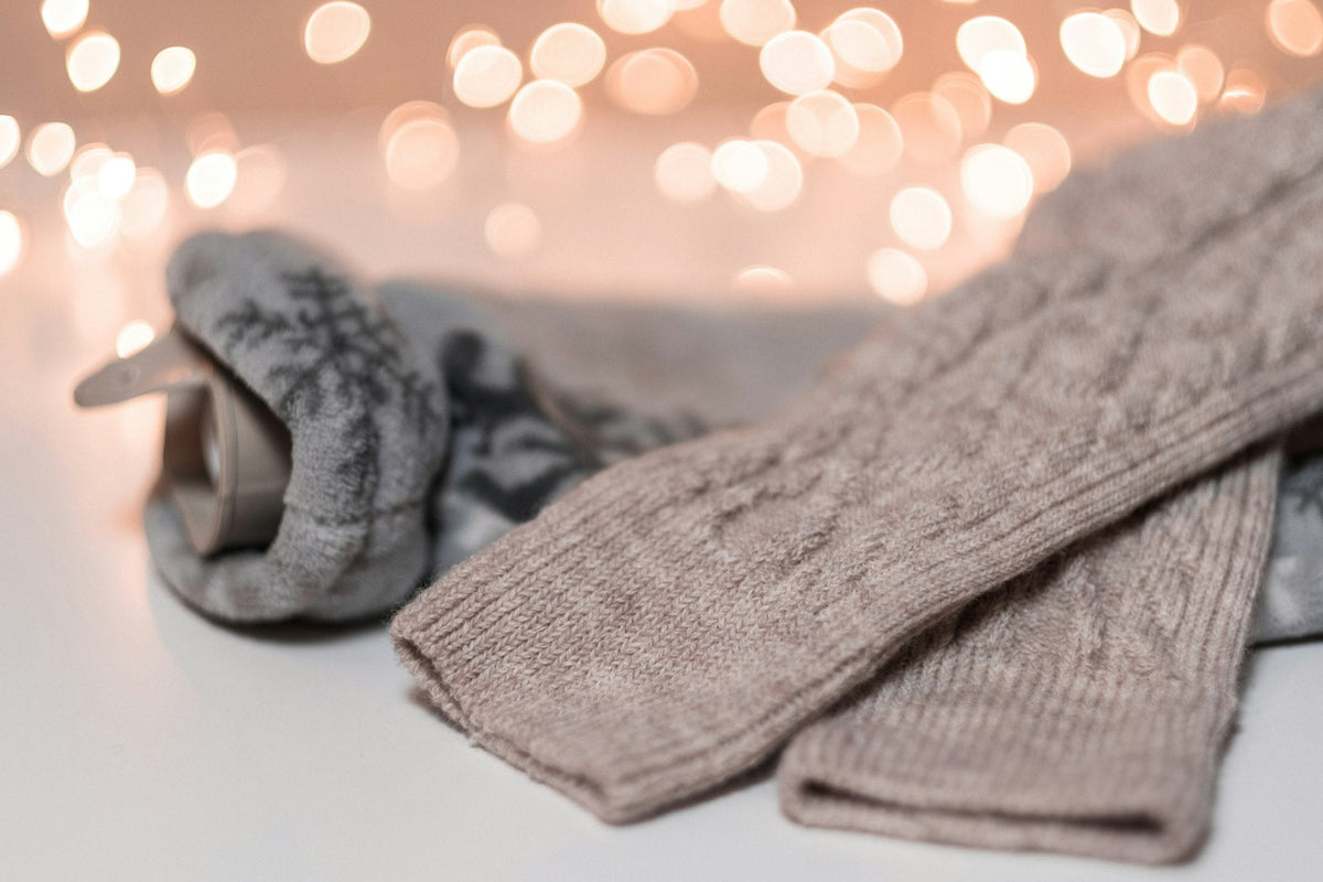 Warme Strick- und Wollsocken auf hellem Untergrund vor Lichterkette im Hintergrund