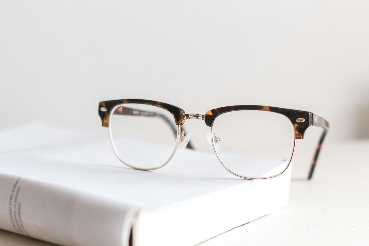 Brille mit Schildpattfassung auf einem weißen Buch vor hellem Hintergrund
